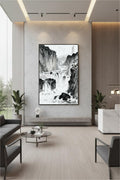 The River Carves Through Stone ink painting in a black frame above a stone ledge with lounge seating in a corporate lobby